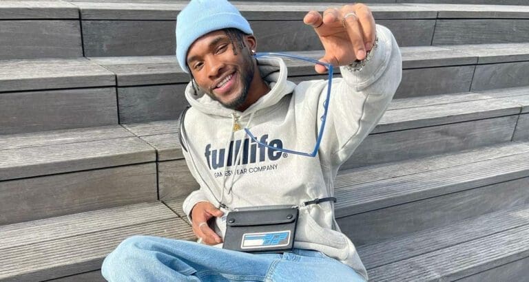man sitting on steps in hoodie and blue beanie