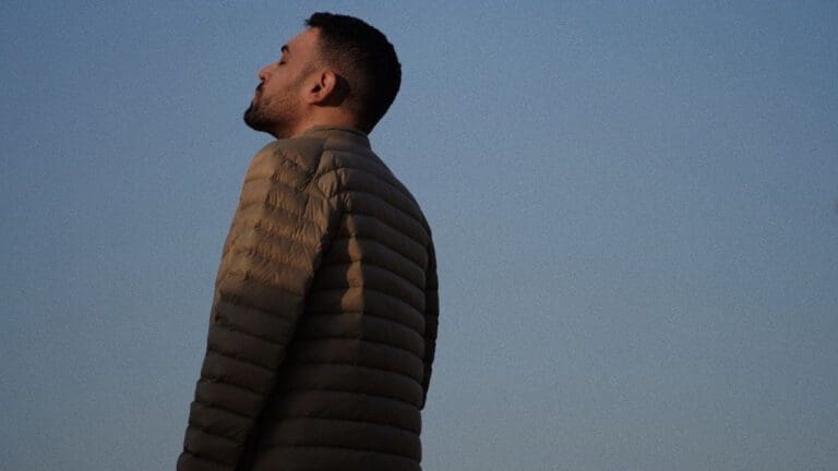 man wearing green jacket looking up to sky