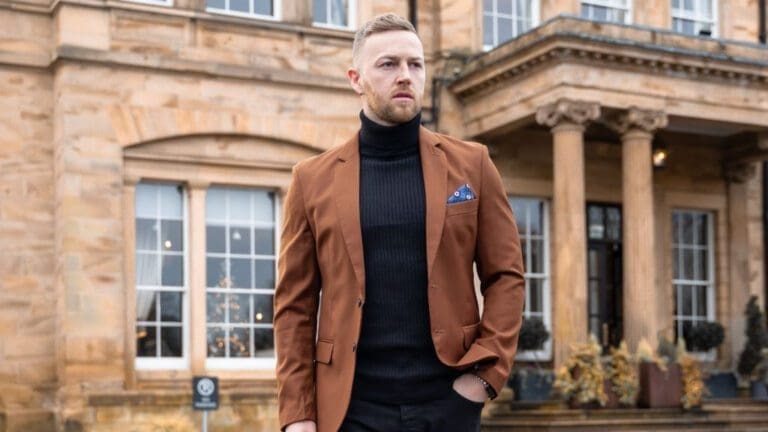 man in brown suit jacket and black roll neck