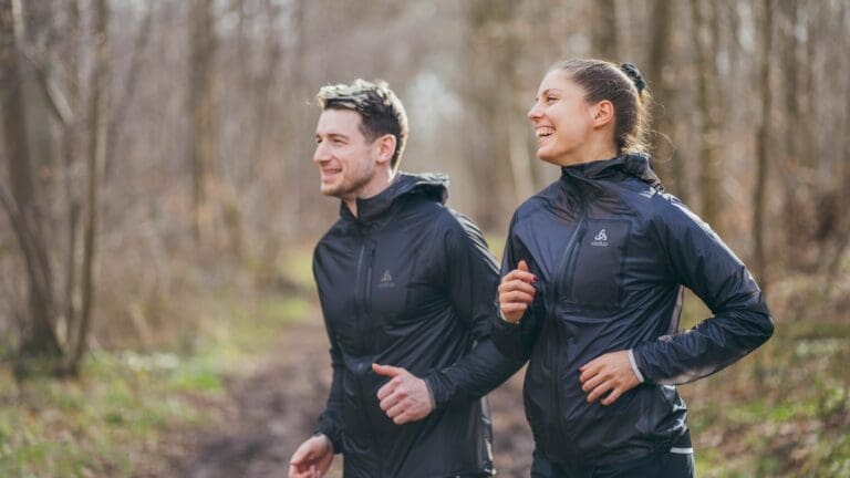 couple running through woods in activewear