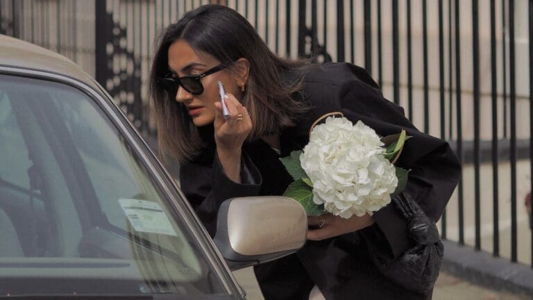 woman applying makeup in car window